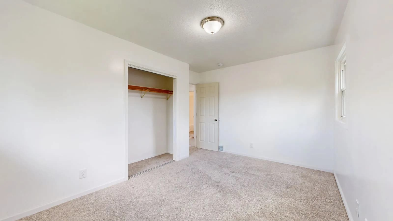 Empty bedroom with fresh wall-to-wall carpet and an open closet, the finished look of a carpet installation