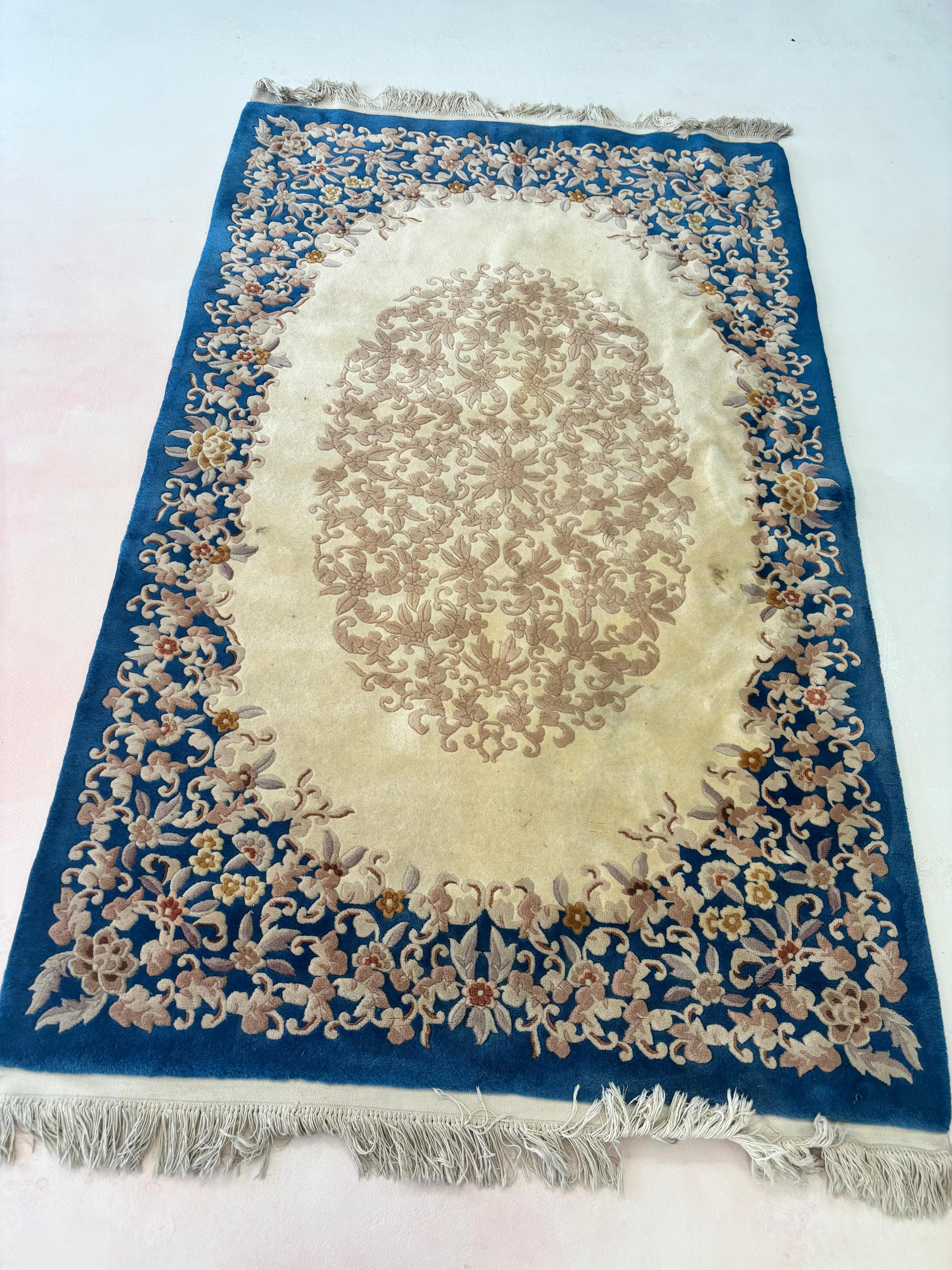 Blue and cream floral area rug with fringe laid out for rug cleaning